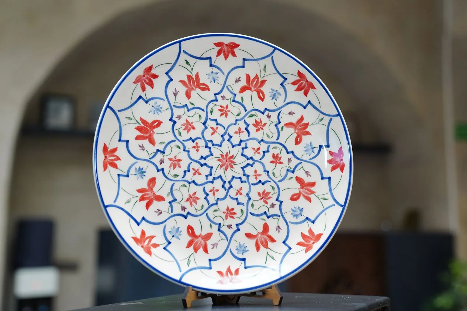 Intricately designed ceramic plate featuring vibrant floral motifs in red, blue, and green.